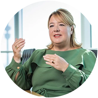 Valentina Daiber speaks, wearing a green blouse, sitting in front of a light background.